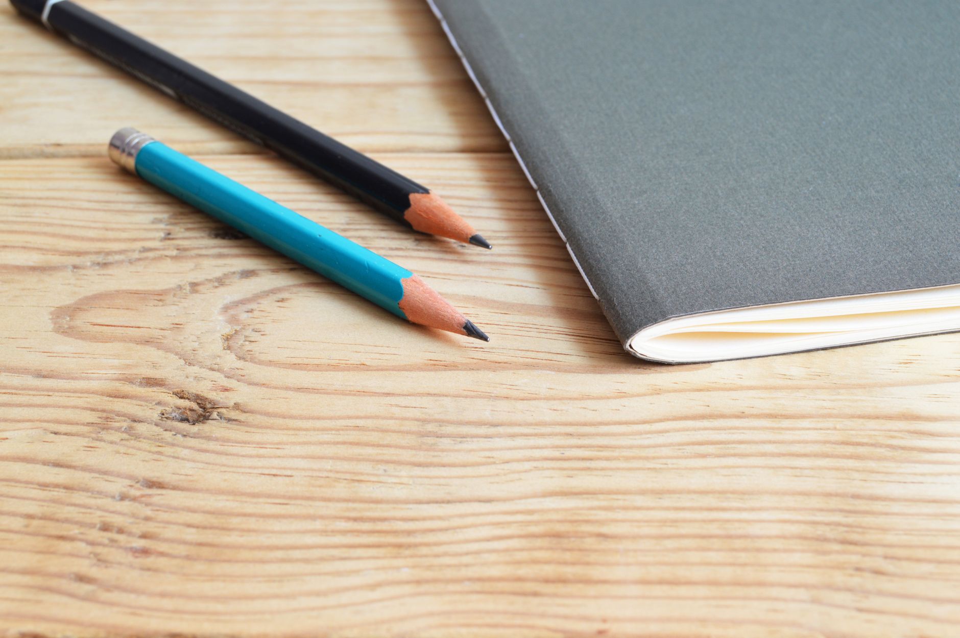 A notebook and two pencils resting on a wooden desk, a simple home-office setup for reputation-management work.